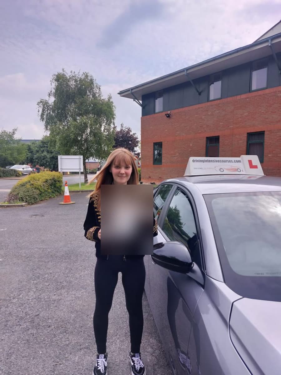 Learner celebrating a practical-test pass beside a Driving Intensive Courses car