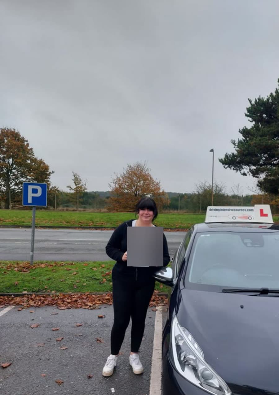 Learner celebrating a practical-test pass beside a Driving Intensive Courses car