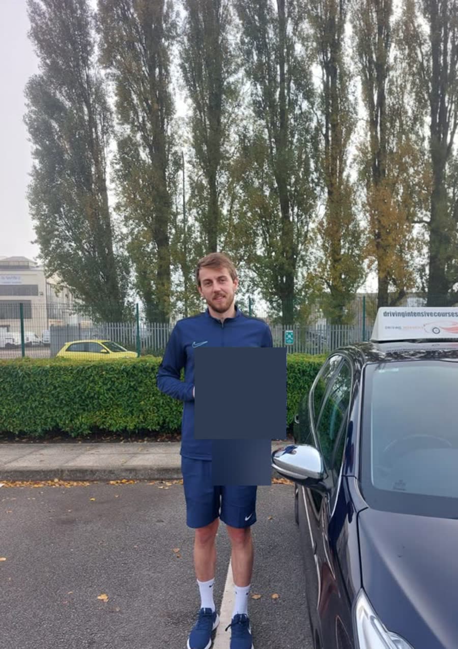 Learner celebrating a practical-test pass beside a Driving Intensive Courses car