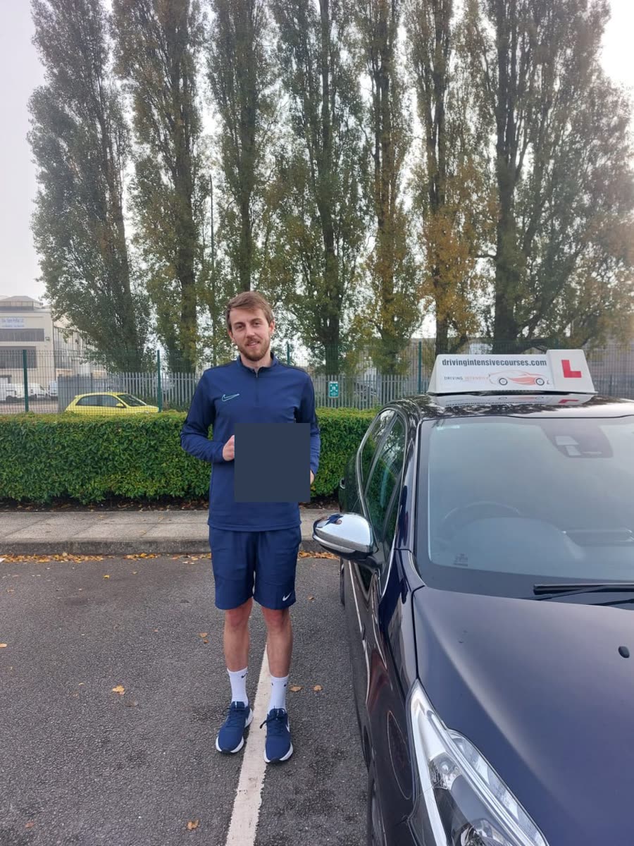 Learner celebrating a practical-test pass beside a Driving Intensive Courses car