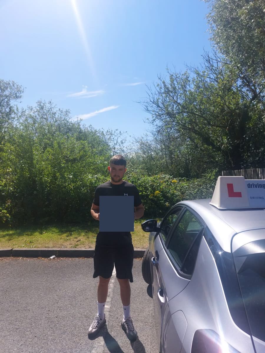 Learner celebrating a practical-test pass beside a Driving Intensive Courses car