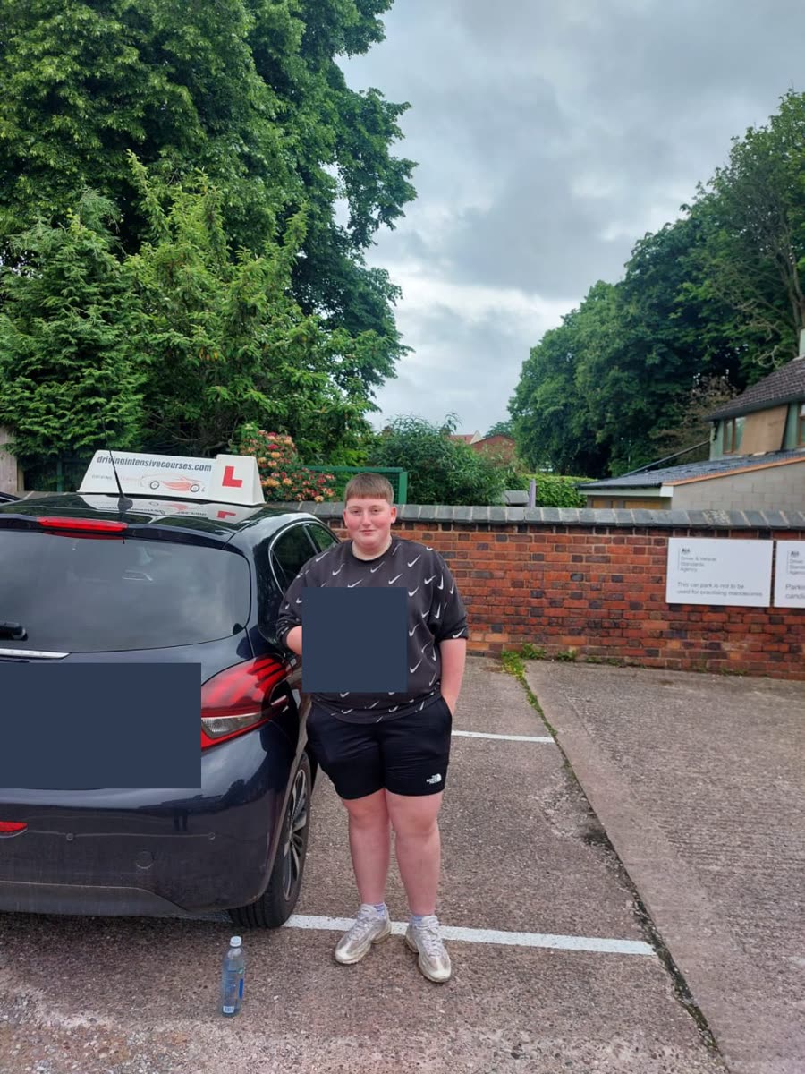 Learner celebrating a practical-test pass beside a Driving Intensive Courses car