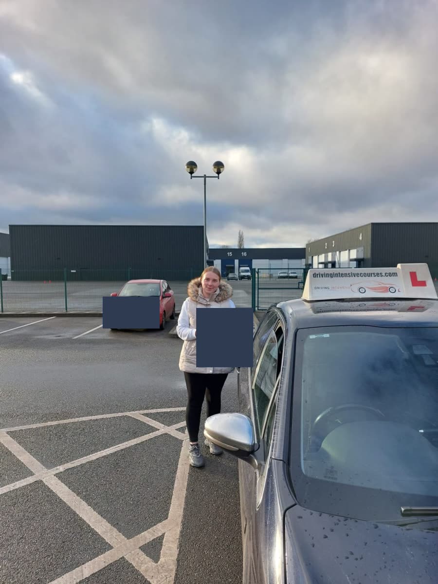 Learner celebrating a practical-test pass beside a Driving Intensive Courses car